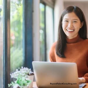 image of woman smiling at camera over her open laptop